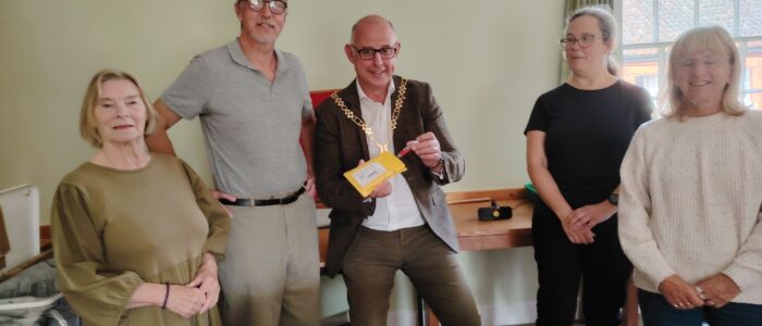 Cllr Stuart Dark completes the first dispatch Councillor Dark places the first USB copy of today's Mardler into a mailing wallet watrched carefully by members of the Copy and Dispatch team.